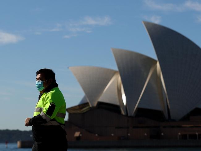 A man wearing a face mask walks past the Opera House in Sydney on July 13, 2021, during a lockdown as authorities stepped up efforts to curb a fast-growing coronavirus outbreak. (Photo by Brendon THORNE / AFP)