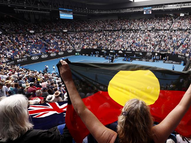 MELBOURNE, AUSTRALIA - JANUARY 24:  A spectator in the crowd holds up an Indigenous flag after Ashleigh Barty of Australia wins her Women's Singles third round match against Elena Rybakina of Kazakhstan on day five of the 2020 Australian Open at Melbourne Park on January 24, 2020 in Melbourne, Australia. (Photo by Darrian Traynor/Getty Images)