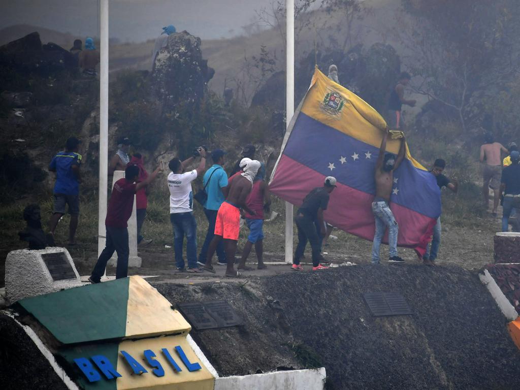 Demonstrators opposed to the government of Nicolas Maduro take down a Venezuelan flag on the border between Venezuela and Pacaraima, Roraima state, Brazil, where clashes erupted amid efforts to take aid into the crisis-hit country. Picture: AFP