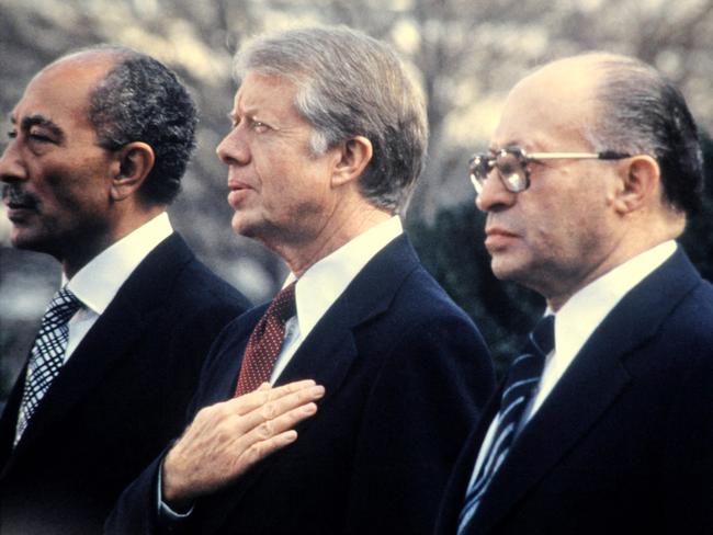 (FILES) Egyptian President Anwar al-Sadat (L), US President Jimmy Carter (C) and Israeli Premier Menachem Begin (R) listen to national anthems before signing the historic US-sponsored Mideast peace treaty between Israel and Egypt on March 26, 1979 on the north lawn of the White House  in Washington, DC. Carter, the 100-year-old former US president and Nobel peace laureate who rose from humble beginnings in rural Georgia to lead the nation from 1977 to 1981, has died, his nonprofit foundation said on December 29, 2024. (Photo by CONSOLIDATED NEWS / AFP)