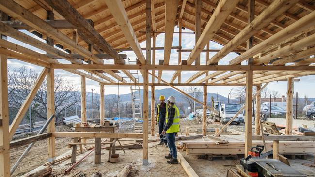 Construction workers in building site of wooden house.