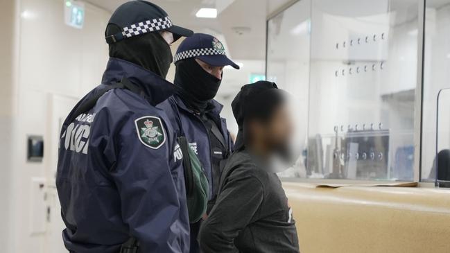 Accused terrorism recruiter Neil Prakash is escorted by police officers after arriving at Darwin Airport from Turkey on Friday. Picture: AFP