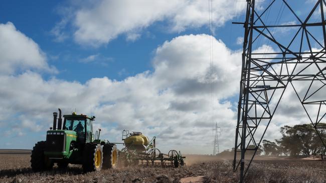 A tractor cropping beside transmission lines.