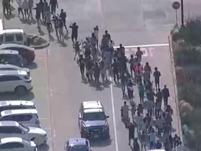 Shoppers leave with hands up as police respond to a shooting in the Dallas area's Allen Premium Outlets. Picture: ABC Affiliate WFAA