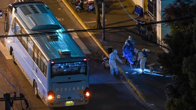 Health workers wearing personal protective equipment prepare a resident and a boy to board a bus in locked down Jing'an district in Shanghai on Monday. Picture: AFP