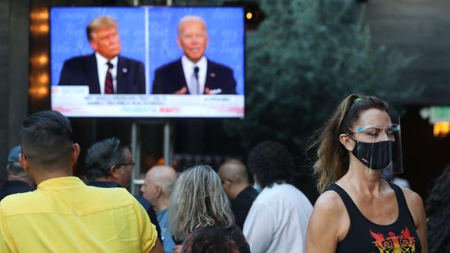 A server wears a face shield and face covering as people sit and watch a broadcast of the first debate between President Donald Trump and Democratic presidential nominee Joe Biden at The Abbey in West Hollywood, California. Picture: AFP