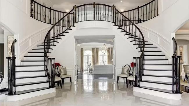 The mansion features dual sweeping staircases to the second level.