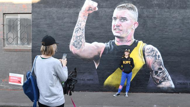 Tigers fans get a selfie with a mural of Brownlow Medal winner Dustin Martin in Richmond. Picture: AAP