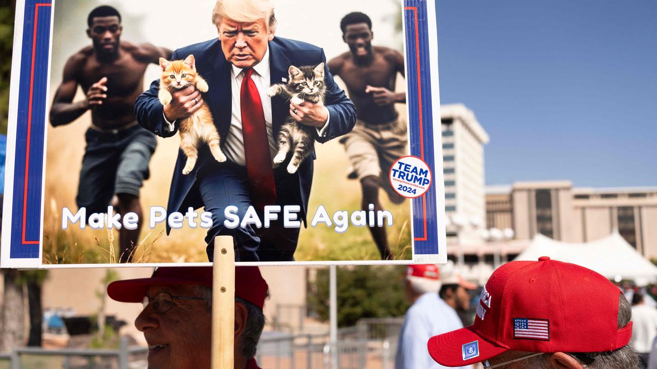 A man carries an AI-generated image of former US President and Republican presidential candidate Donald Trump carrying cats away from Haitian immigrants, a reference to falsehoods spread about Springfield, Ohio, during a campaign rally for Trump at the Tucson Music Hall in Tucson, Arizona, September 12, 2024. (Photo by Rebecca NOBLE / AFP)