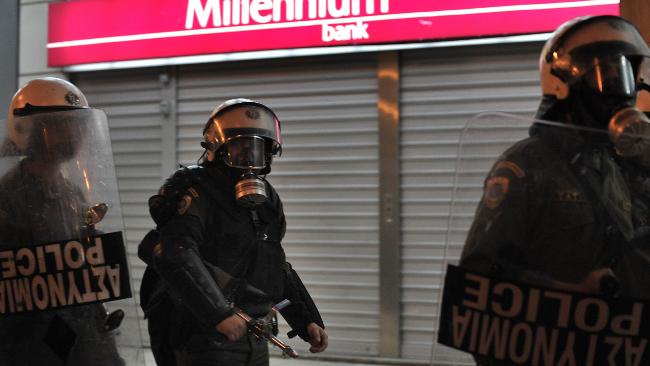 Riot police guard a bank in Athens during protests over the Greek Government's handling of the economy / AFP