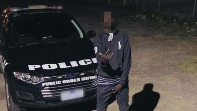 A youth posing with a Victoria Police car.