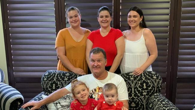 Lockdowns mean Mr Atwood’s family have trouble seeing him in hospital. At Christmas with his three daughters (back row l-r: Samantha Atwood, Courtney Mowat, Gabrielle Atwood; on his lap l-r: Harper Sledge &amp; Arabella Mowat) and two of his three grandchildren. Supplied.