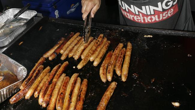 Sausages being cooked, or “sizzled” as the Aussies say it, on company grills in the parking lots of Australian hardware chain, Bunnings. (Pic: News Corp)