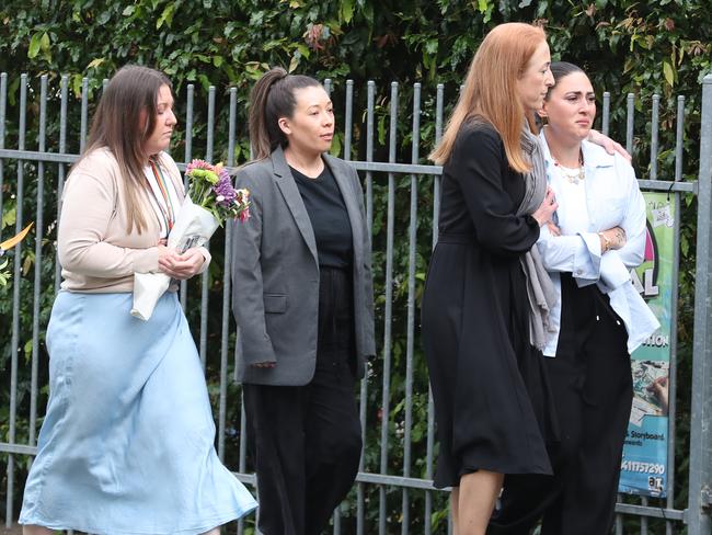 Teachers and parents arrive at the school with floral tributes. Picture: David Crosling