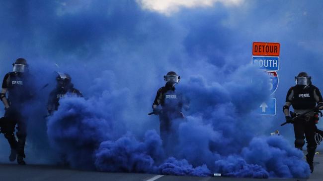 Police in riot gear walk through a cloud of blue smoke as they advance on protesters near the Minneapolis 5th Precinct.