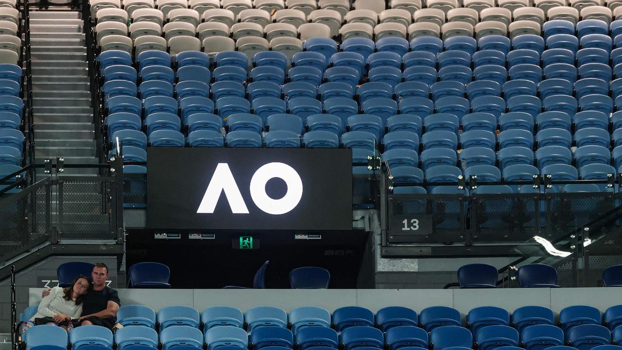 Two spectators watch the men's doubles final in a mostly empty Rod Laver Arena. (Photo by DAVID GRAY / AFP)