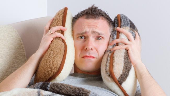 CAREERS: Man holding head on pillows, concept of headache, overworked, pain, sick