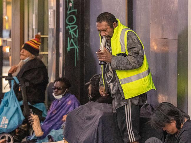 A group of people who appear to be sleeping rough openly take drugs and drink alcohol.