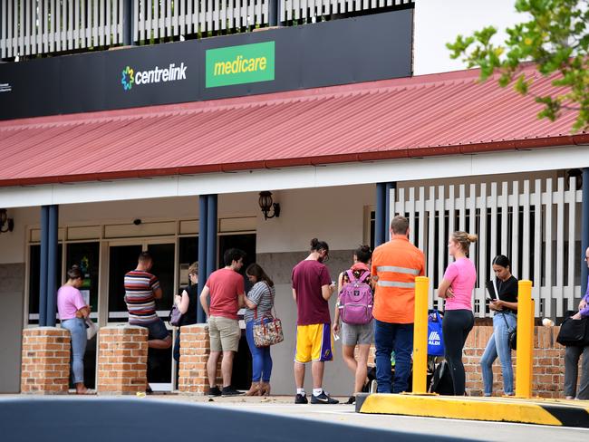 People are seen in a long queue outside a Centrelink office in Brisbane, Tuesday, March 24, 2020. Centrelink offices around Australia have been inundated with people attempting to register for the Jobseeker allowance in the wake of business closures due to the COVID-19 pandemic. (AAP Image/Dan Peled) NO ARCHIVING