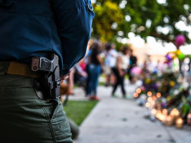 A police officer visits a makeshift memorial outside the Uvalde County Courthouse. Picture: Chandan Khanna/AFP