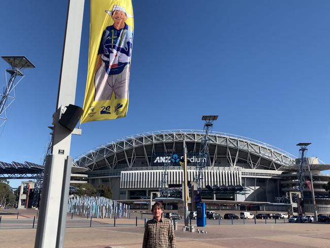 Terry Carr under an image of himself on a banner at Sydney Olympic Park. Picture: Supplied.