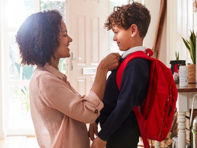 Single Mother At Home Getting Son Wearing Uniform Ready For First Day Of School