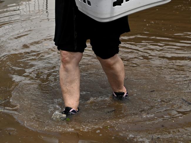 WOODBURN, AUSTRALIA - MARCH 07: Patria Powell walks through floodwater after salvaging items from her mother's flood-affected home March 07, 2022 in Woodburn, Australia.  Residents of northern New South Wales are still cleaning up following unprecedented storms and the worst flooding in a decade. (Photo by Dan Peled/Getty Images)