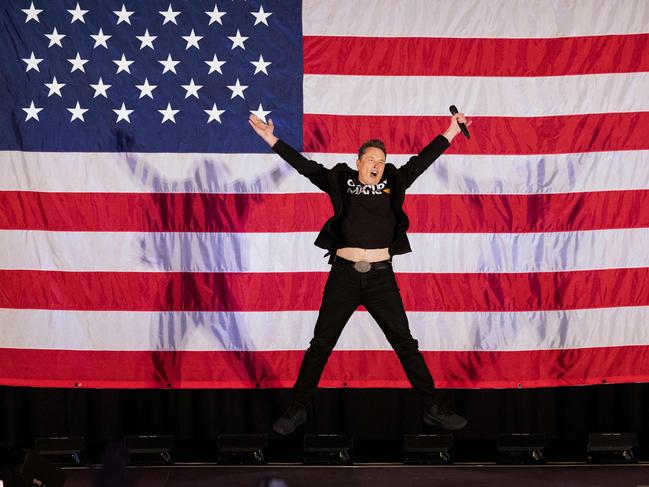 TOPSHOT - Tesla and SpaceX CEO Elon Musk jumps on stage as he arrives to speak at a town hall event hosted by America PAC in support of former US President and Republican presidential candidate Donald Trump at the Greater Philadelphia Expo Center in Oaks, Pennsylvania, on October 18, 2024. Musk is holding several events in the key swing-state of Pennsylvania in support of former US President and Republican presidential candidate Donald Trump. (Photo by RYAN COLLERD / AFP)