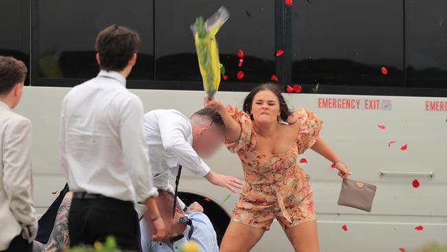 A woman whacks one of the men on the head with her flowers, sending petals flying. Picture: Mark Evans/Getty Images