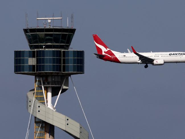 This picture taken on December 6, 2023 shows a Qantas Airways Boeing 737-800 passenger aircraft on final approach for landing in front of the control tower at Sydneyâs Kingsford Smith international airport. (Photo by DAVID GRAY / AFP)