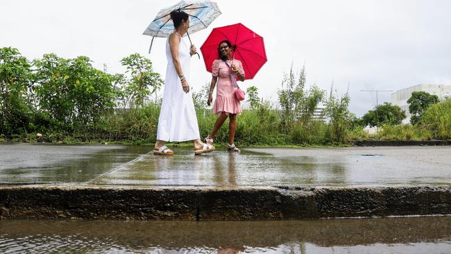 Wet weather remains stubbornly persist across Far North Queensland, with a monsoon trough bringing periods of rain and shower activity to Cairns. Renee Moseley and Meena Rastoka have a chat and a laugh as the walk along a soggy Hartley Street in the city. Picture: Brendan Radke