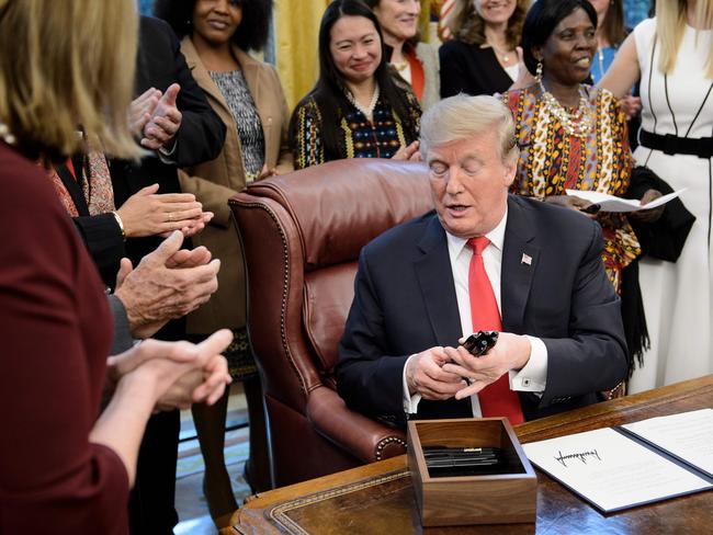 US President Donald Trump hands out pens after signing a presidential order during an event to launch the Women's Global Development and Prosperity Initiative in the Oval Office of the White House February 7, 2019 in Washington, DC. (Photo by Brendan Smialowski / AFP)