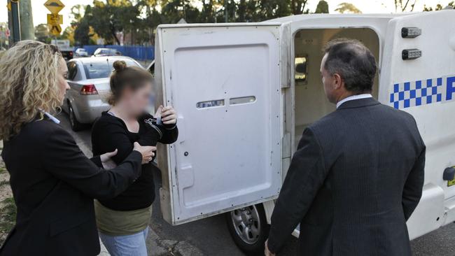 Detectives take a women into custody, one of five people arrested after investigations into the alleged prostitution of children in Sydney’s southwest