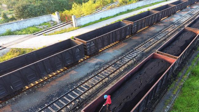 A worker leveling coal on a carrier in Jiujiang, in China's central Jiangxi province. Picture: AFP