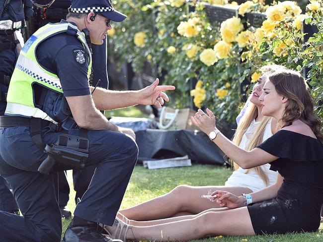 Police at Flemington racecourse chat to two girls on the field in the late afternoon. Picture: AAP.