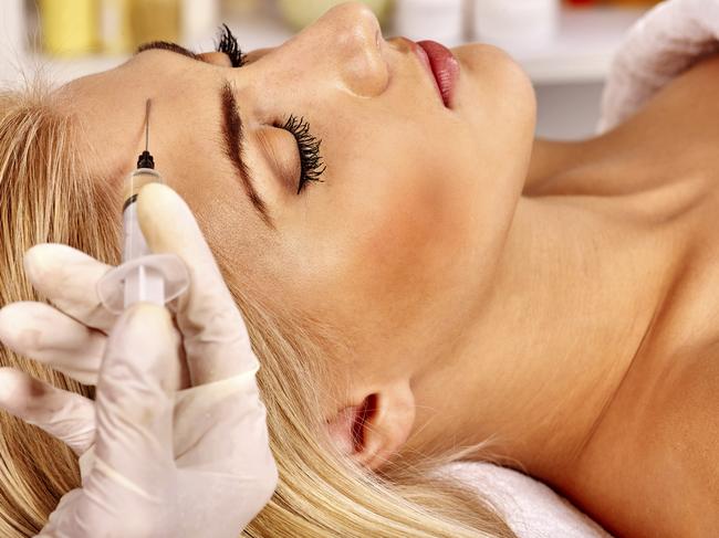 Beauty woman giving botox injections on forehead.