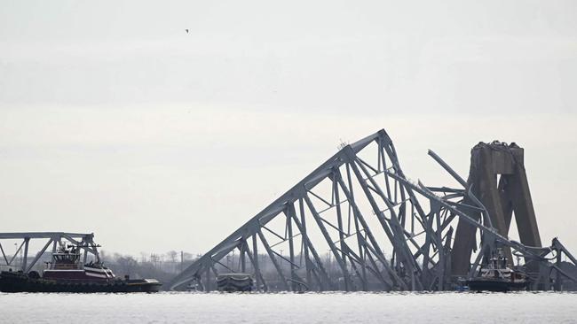 The steel frame of the Francis Scott Key Bridge lies in the water. (Photo by Mandel NGAN / AFP)