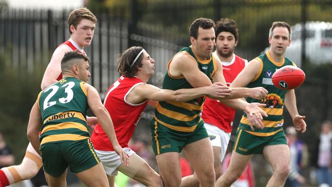 Peter Butler of North Brunswick handpasses under pressure from Marco Creek of Parkside during Saturday’s VAFA Division 4 decider. Picture: Hamish Blair