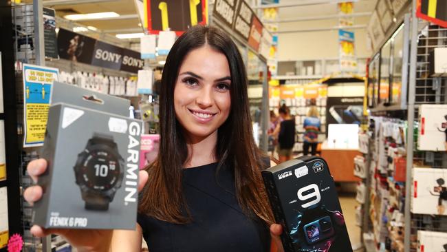 Mia Cygler from Cairns Central holds a Garmin watch and a GoPro Hero 9, two of the most sought after Christmas gifts at JB Hi Fi. Picture: Brendan Radke