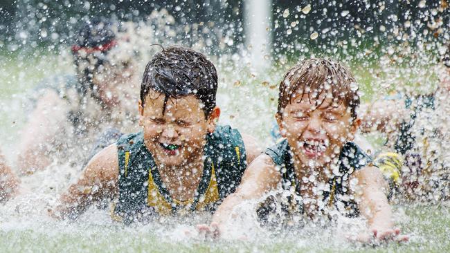 Maroochydore Roos Under 10s players take a post game slide on their saturated AFL oval as torrential rain and flash flooding continues across south east Queensland. Picture Lachie Millard