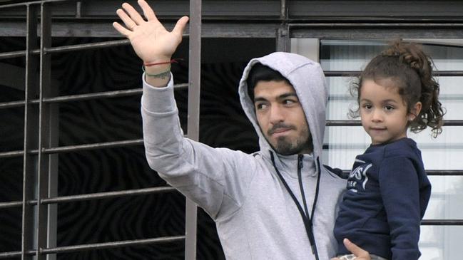 Uruguay's soccer player Luis Suarez holds his daughter as he greets fans from their home's balcony on the outskirts of Montevideo, Uruguay, Friday, June 27, 2014. Suarez returned to Montevideo early Friday, arriving too late to see the hundreds of Uruguay fans who had gathered the previous night to give him a hero's welcome despite his World Cup banishment. (AP Photo/Matilde Campodonico)