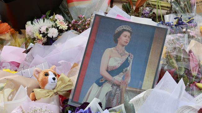 Mourners lay flowers at the base of a statue of Queen Elizabeth II at Government House.