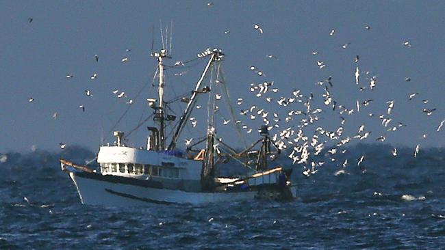 A fishing trawler returns to Newcastle Port followed by a flock of hungry seagulls as a storm brews at sea on dawn. Picture by Peter Lorimer.