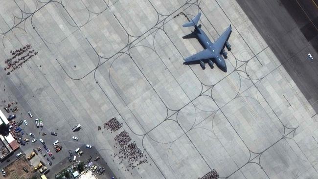 This satellite image shows crowds of people waiting on the tarmac at Kabul’s Hamid Karzai International Airport in Afghanistan, with a c17 transport aircraft ready, on August 23. Picture: Maxar Technologies/AFP