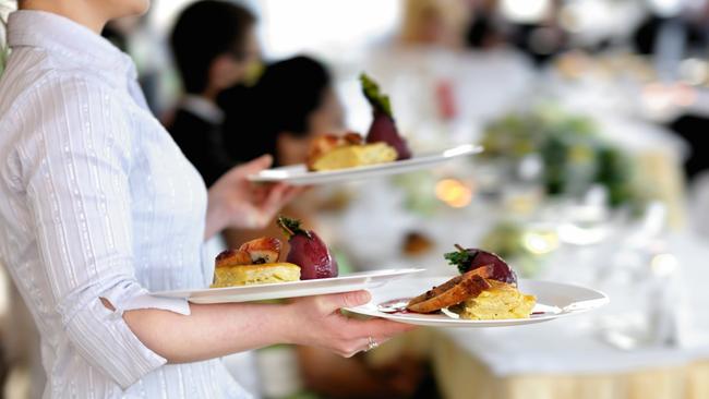 Waitress carrying three plates with meat dishGeneric photo of woman working in hospitality industry