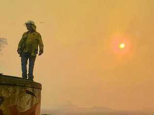 Ewingar burns as RFS assess the situation from a water tank. Picture: Nadine Gaffney