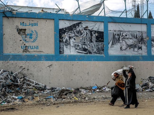 People walk past the damaged Gaza City headquarters of the United Nations Relief and Works Agency for Palestine Refugees (UNRWA) on February 15, 2024, amid ongoing battles between Israel and the militant group Hamas. Several countries -- including the United States, Britain, Germany and Japan -- have suspended funding to the UNRWA agency in response to Israeli allegations that some of its staff members participated in the October 7 attack by Hamas militants. (Photo by AFP)