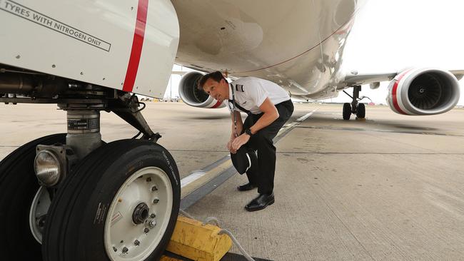 Virgin pilot Ian Morrison performs a pre-flight inspection at Brisbane Airport on Thursday. Picture: Lyndon Mechielsen