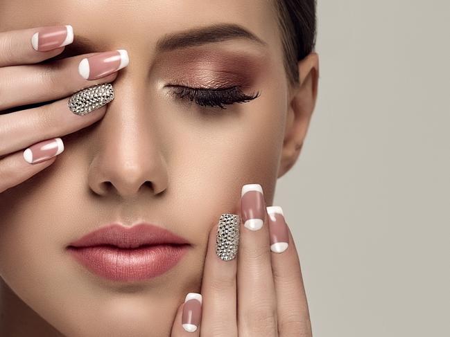 Young appealing woman is showing pale-pink french style manicure with  rhinestone on the slender fingers. Perfect makeup and trendy manicure.  - picture istock