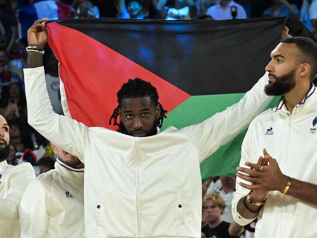 Silver medallists France's #26 Mathias Lessort (C-R), holding the flag of the French overseas department and region of Martinique, and teammates pose on the podium after the men's Gold Medal basketball match between France and USA during the Paris 2024 Olympic Games at the Bercy  Arena in Paris on August 10, 2024. (Photo by Damien MEYER / AFP)